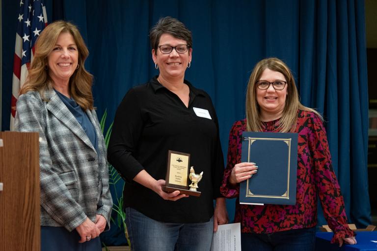 Vicky Fuller and Nancy Maurer accept the golden Henny award from BCPL board member Mary Ellen Wells.