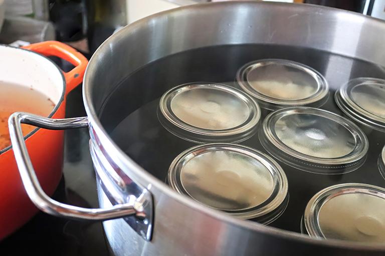 water bath canner; large, stainless steel pot filled with water and several canning jars